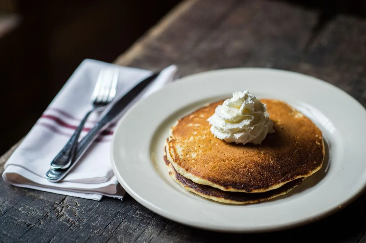 Pancakes topped with cream on a café table